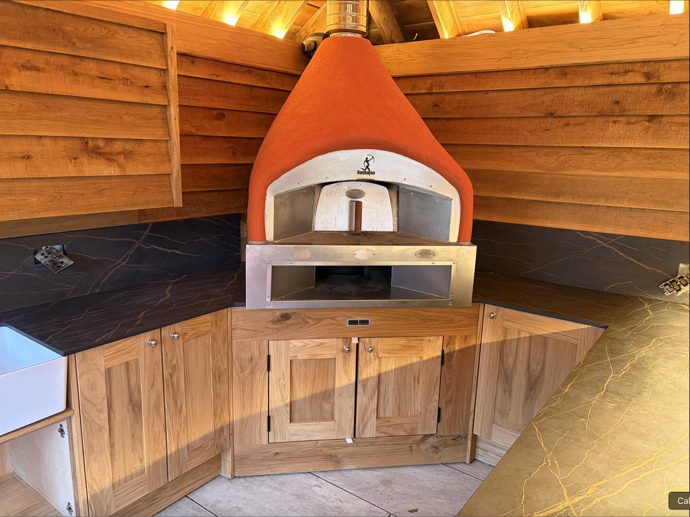 Bespoke outdoor pizza oven kitchen with oak cabinets and marble worktop in St Neots by Cromwell Interiors